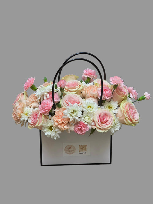Elegant floral basket arrangement with blush roses, carnations, chrysanthemums, and soft pastel blooms in a luxury gift basket.