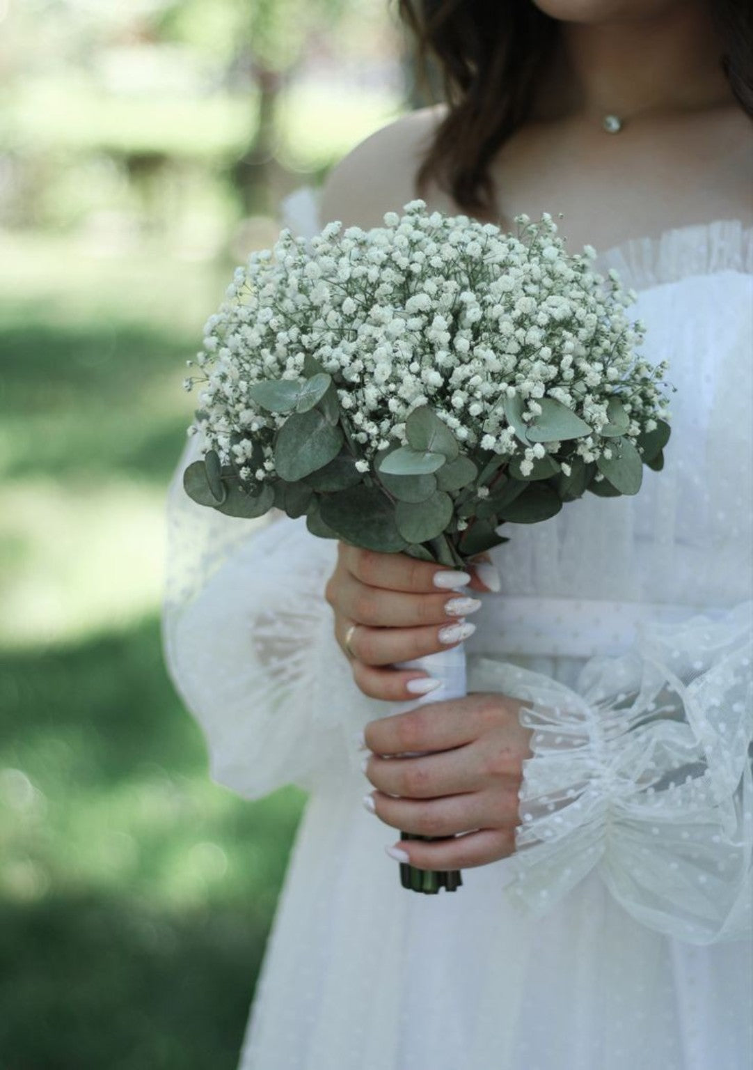 Bride holding a white baby's breath wedding bouquet with eucalyptus