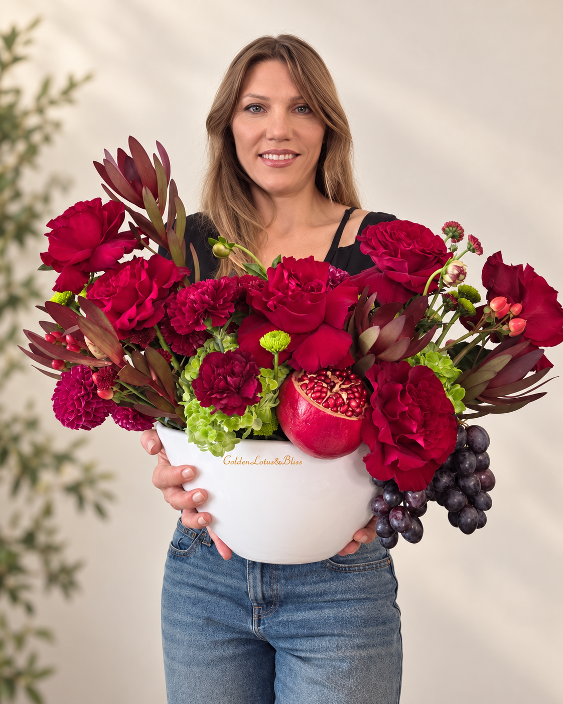 Close view of a burgundy floral and fruit arrangement held by the florist