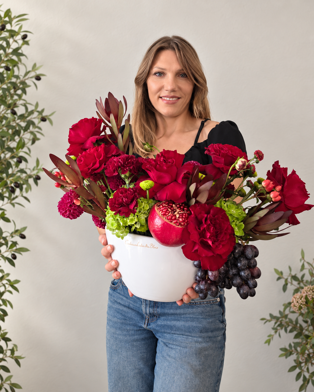 Florist holding a burgundy luxury flower arrangement in a white ceramic boat vase