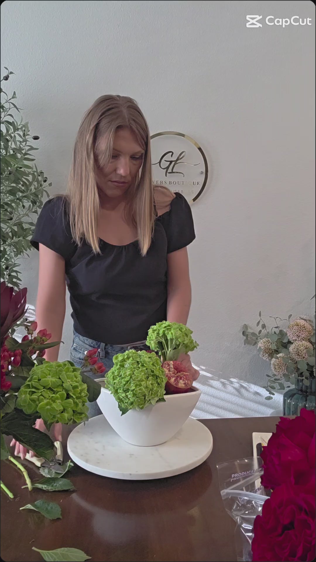 Video of Burgundy Harvest Luxury Arrangement with roses, hydrangea, pomegranate and grapes in a white ceramic boat vase
