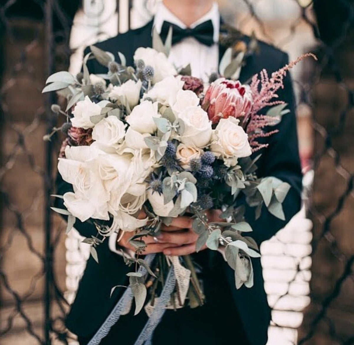 Romantic protea wedding bouquet with white roses and eucalyptus