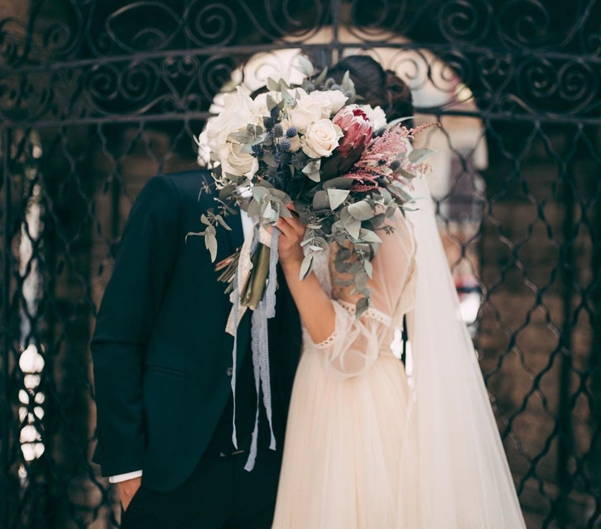 Bride and groom holding a romantic protea wedding bouquet