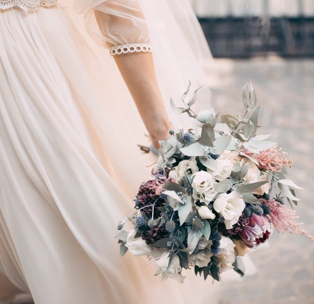 Bride carrying a loose garden-style protea wedding bouquet