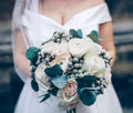 Bride holding a white and blush ranunculus wedding bouquet with eucalyptus