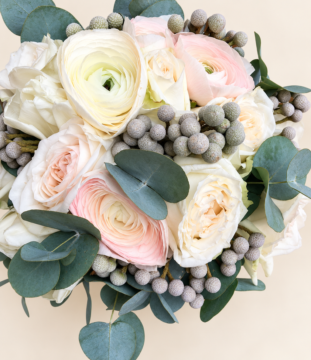 Close-up of white and blush ranunculus bridal bouquet with silver brunia and eucalyptus