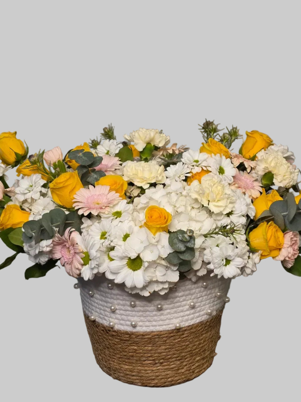 Floral arrangement in a woven basket on a plain background