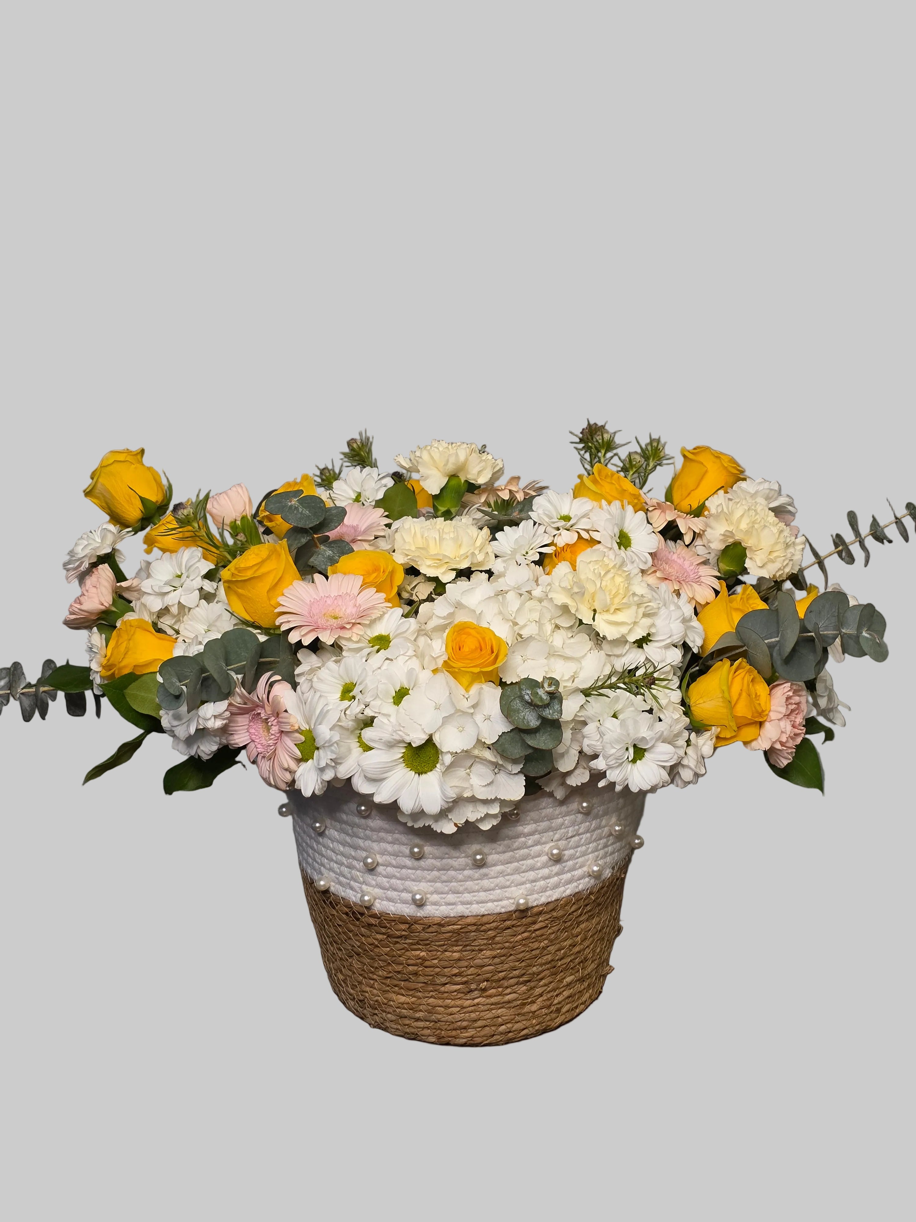 Yellow and white flower basket arrangement with roses, hydrangea, daisies, and eucalyptus